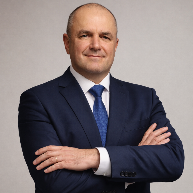 Porträt von Steuerberater Vitalij Kromm in traditioneller Trachtenweste, freundlich lächelnd, vor weißem Hintergrund